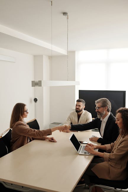 Business professionals engaging in a handshake across a conference table, signifying successful collaboration.